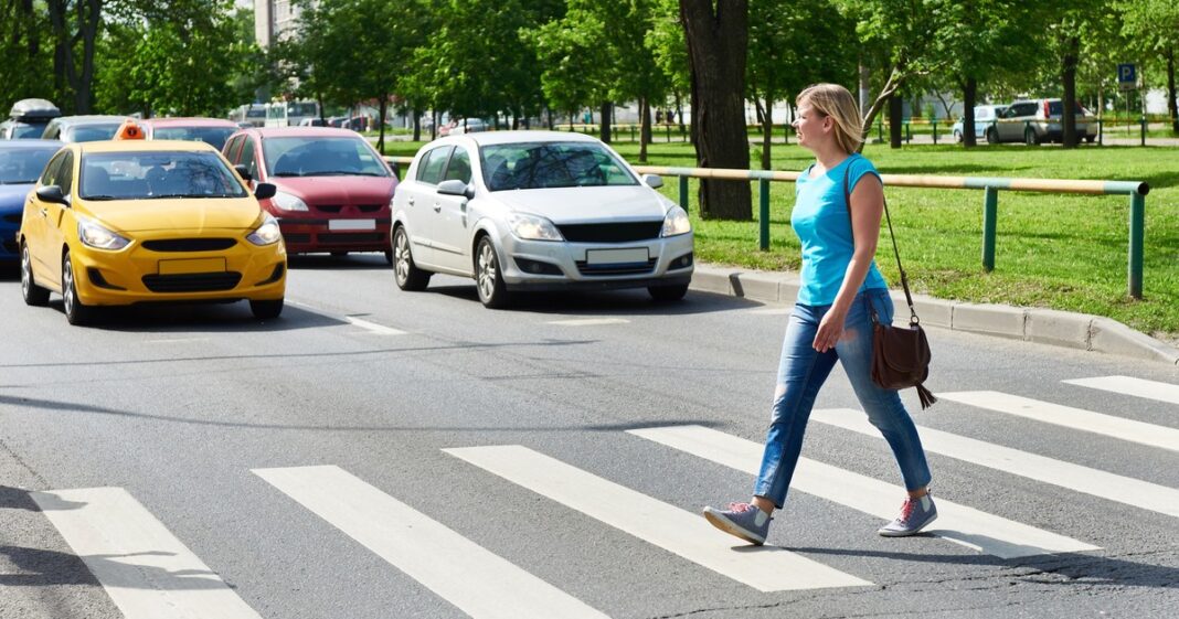 Peatón realizando un gesto de agradecimiento con la mano al cruzar una calle urbana